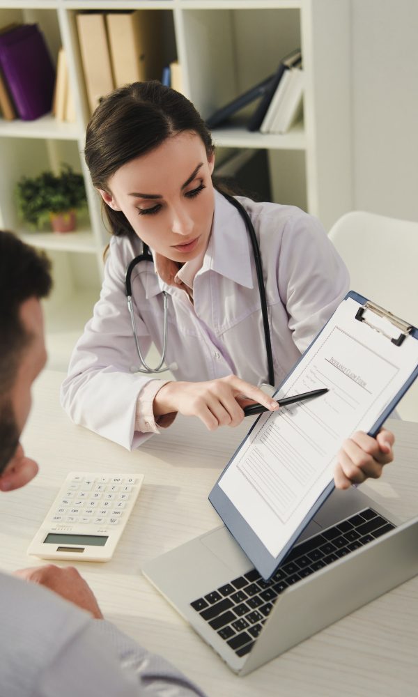 female doctor showing insurance claim form to man in office